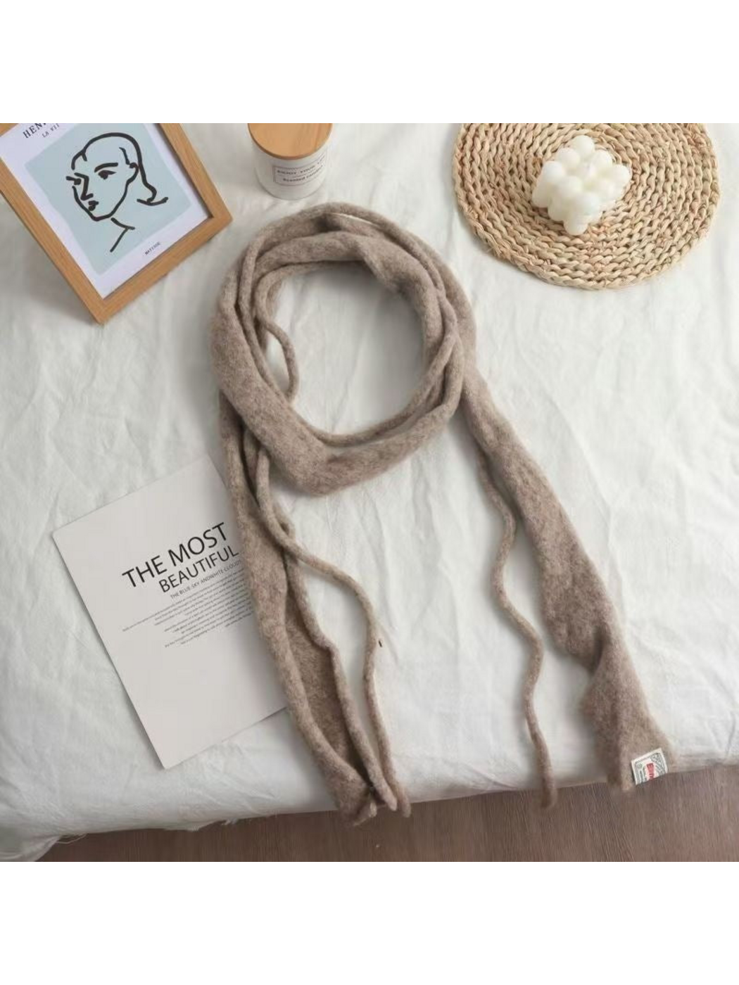 Beige fuzzy narrow scarf arranged in a loose loop with long hanging ends