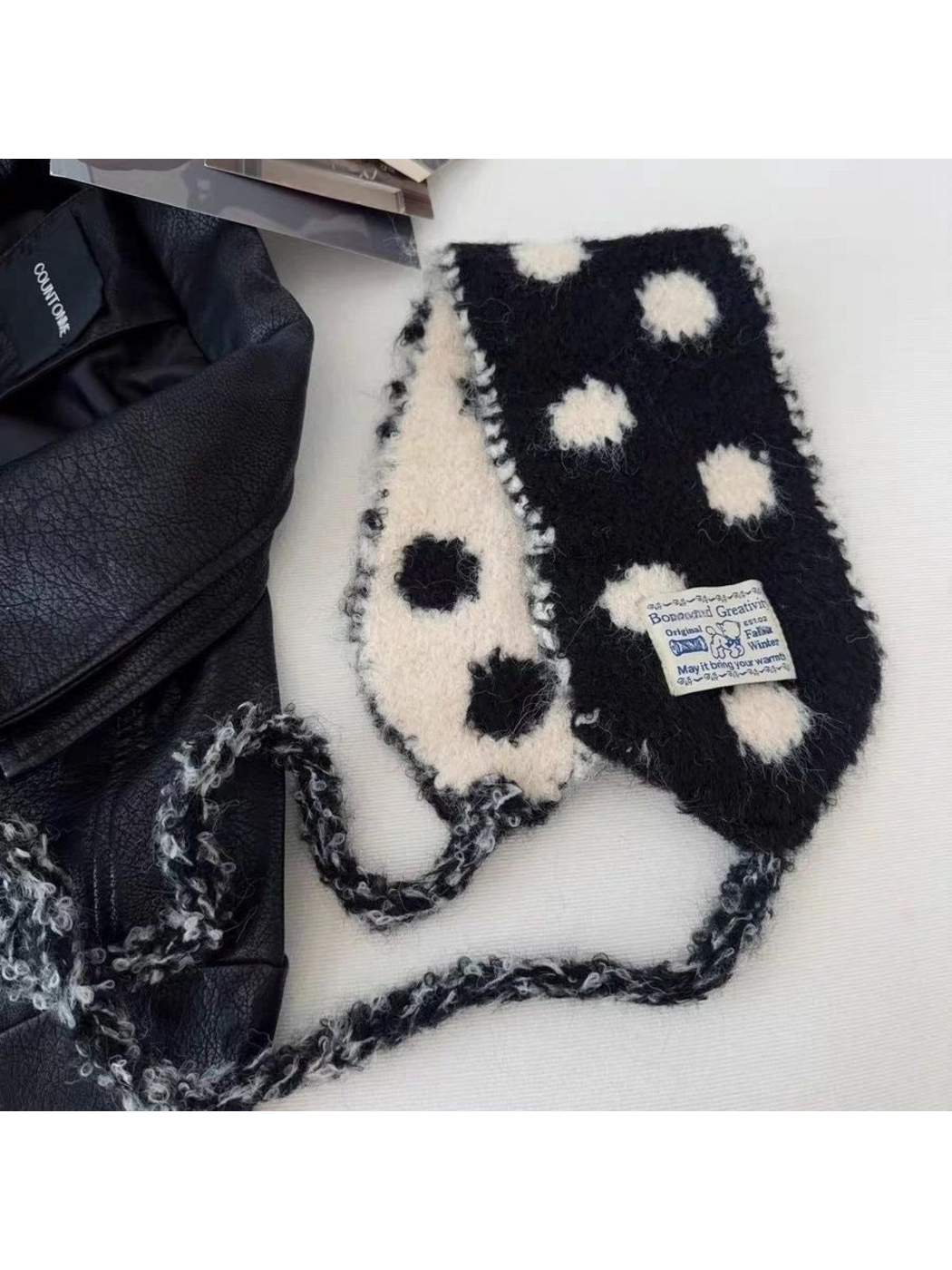 Black polka-dot hood-shaped scarf laid open to show contrasting sides and looped trim