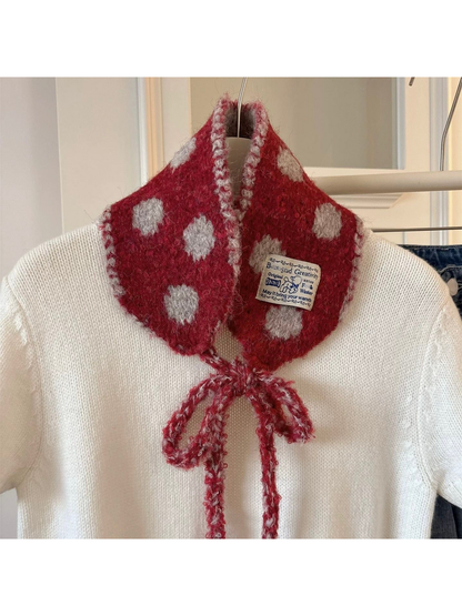 Red polka-dot hood-shaped scarf with bow ties displayed over a white sweater
