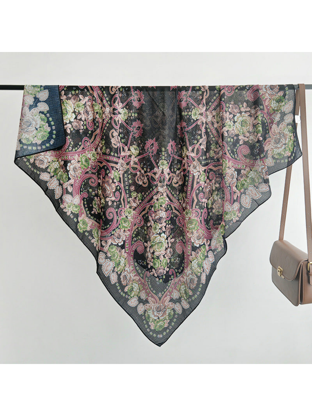 Black floral and paisley scarf folded diagonally over a rail