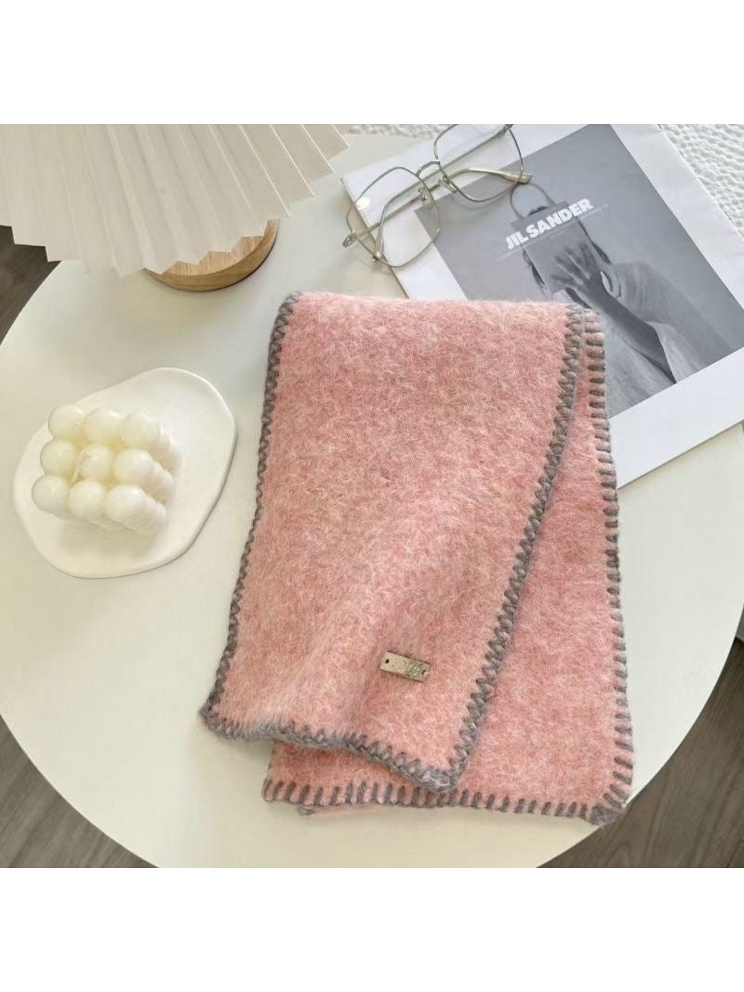 Pink scarf folded on a table with gray blanket-stitched edges