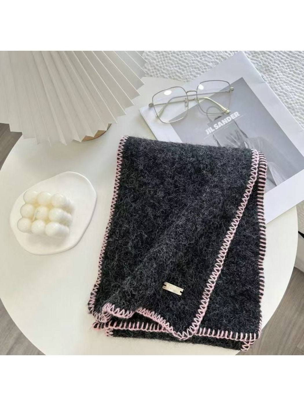 Black scarf folded on a table with pale pink blanket-stitched edges