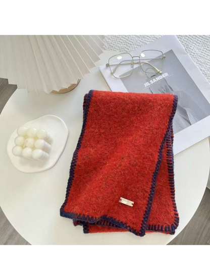 Red scarf folded on a table with dark blanket-stitched edges