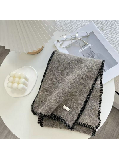 Gray scarf folded on a table with black blanket-stitched edges