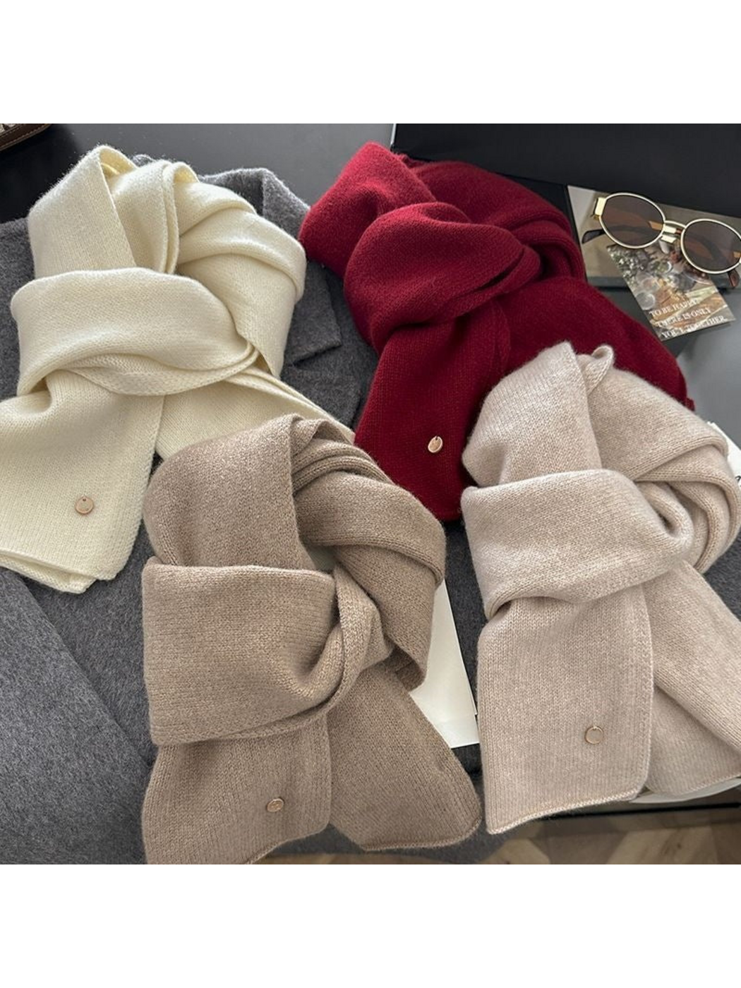 Four solid-color scarves grouped in looped arrangements, showing surface texture and round disc details