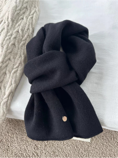 Black scarf in a looped arrangement with broad ends and a round gold-tone disc