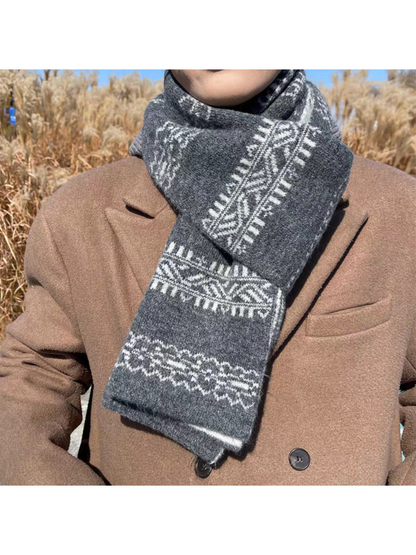Gray snowflake and geometric-band scarf wrapped over a brown coat outdoors