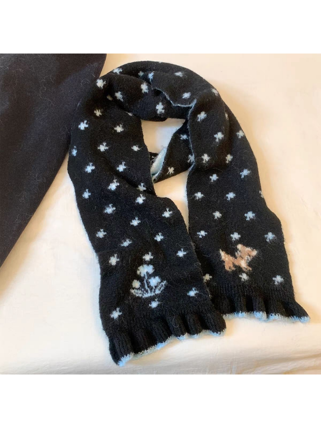 Black scarf in a looped display with pale blue floral motifs, deer design and ruffled ends