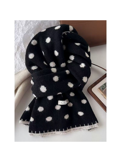 Black polka dot scarf with white dots and edging, looped on a tabletop