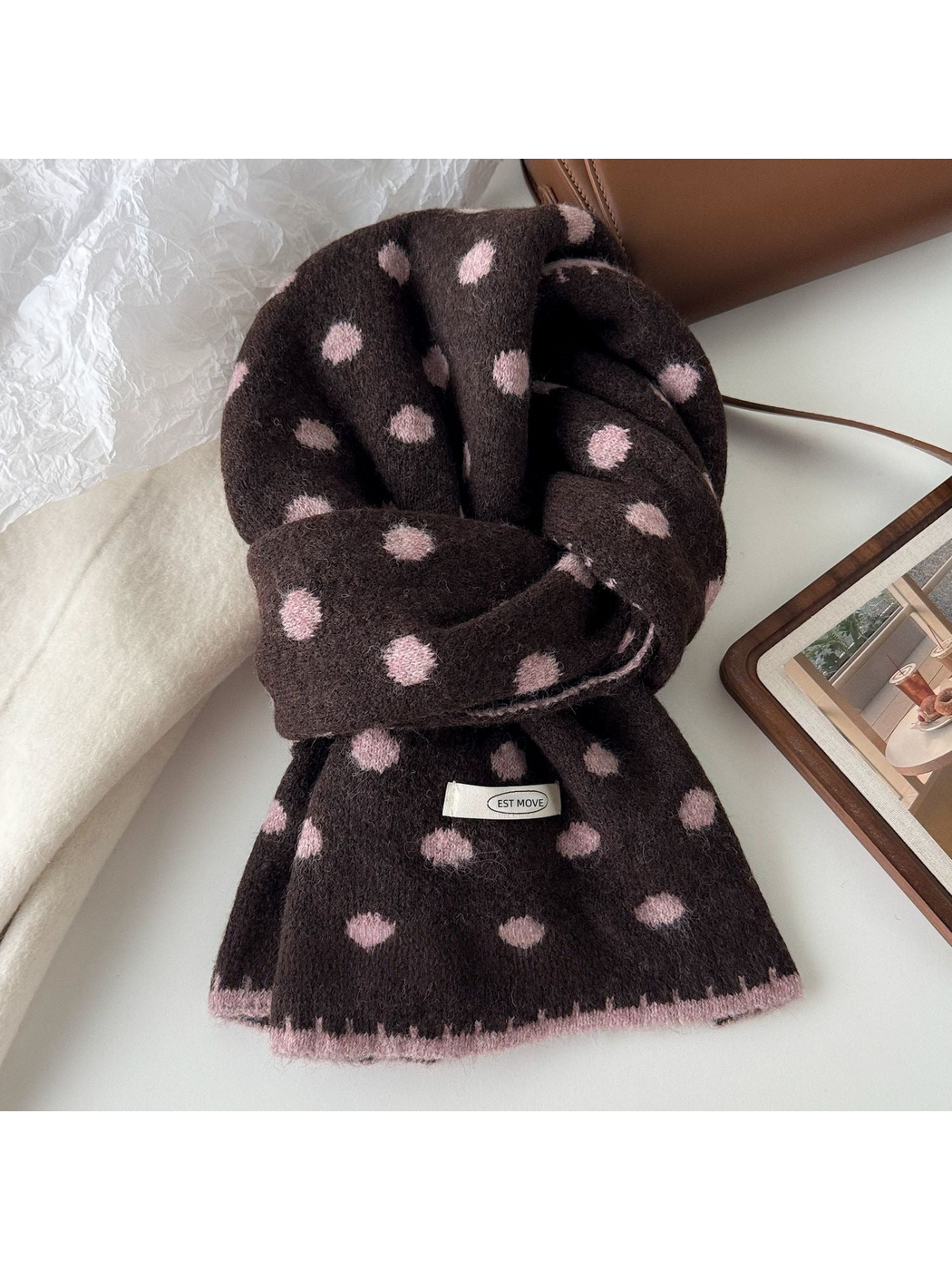 Brown polka dot scarf with pink dots and edging, looped on a tabletop