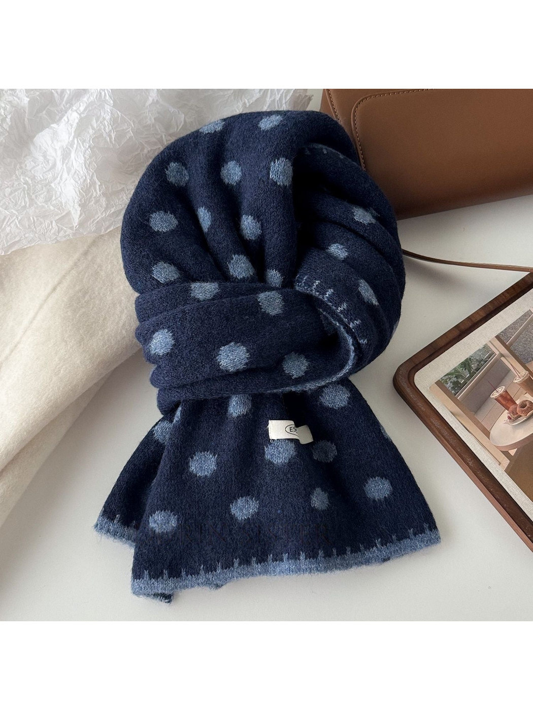Navy polka dot scarf with blue-gray dots and edging, looped on a tabletop