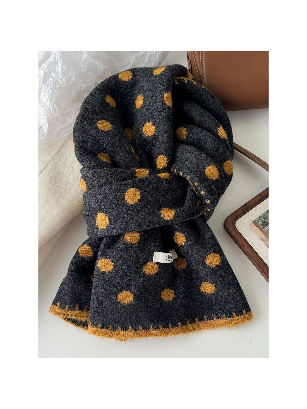 Mustard polka dot scarf with gray ground and mustard-yellow edging, looped on a tabletop