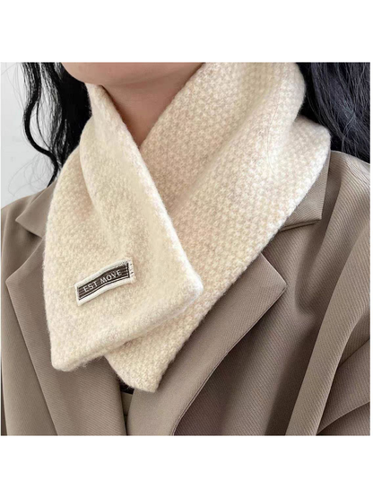 Textured scarf crossed at the neck over a beige jacket