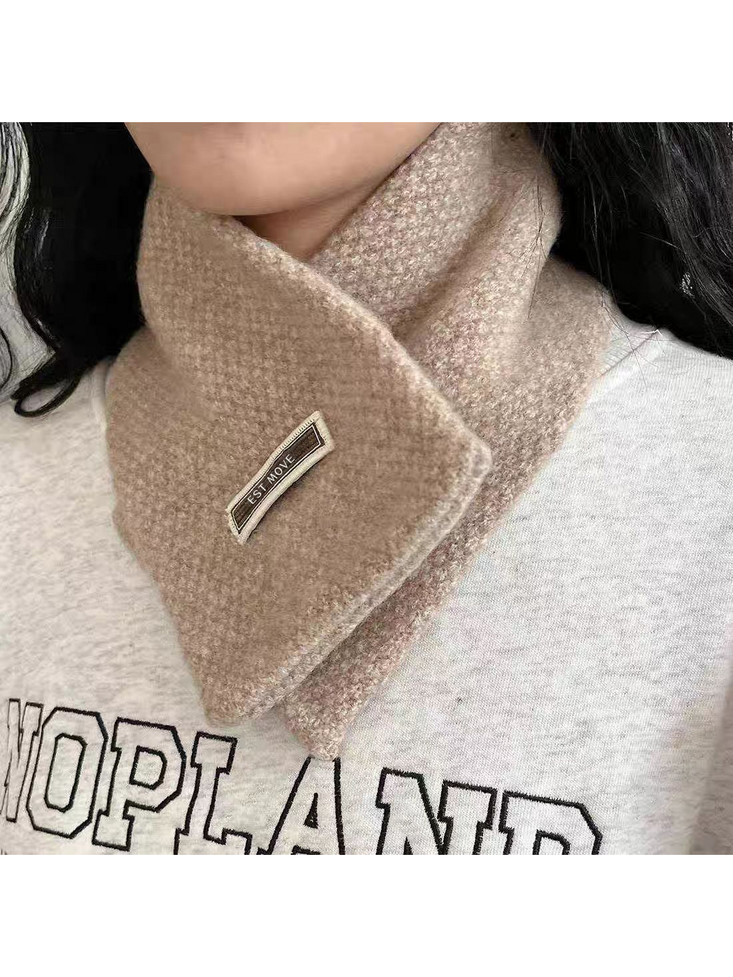 Textured scarf worn crossed at the neck, angled close-up