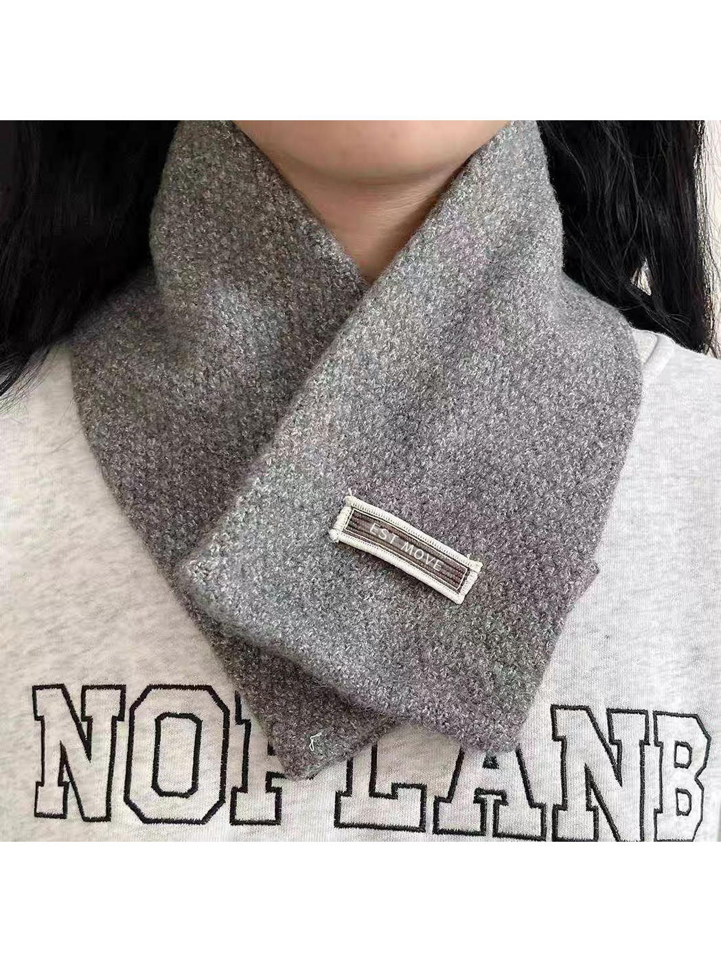 Gray textured scarf worn crossed at the neck, front view