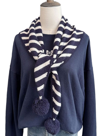 Navy striped triangle scarf with pom-pom ends draped on a mannequin