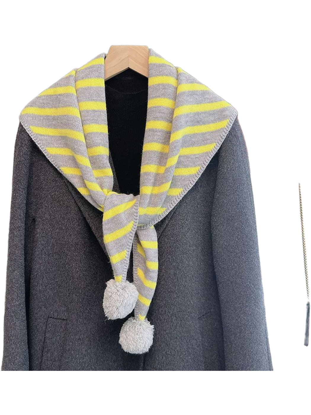 Yellow striped triangle scarf with light gray pom-pom ends over a gray coat