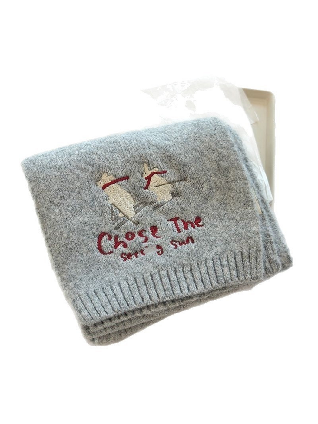 Folded knit scarf showing skiing figures, embroidered lettering and ribbed ends