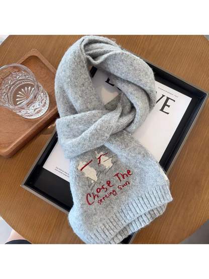 Light Gray scarf in a looped arrangement with skiing embroidery and a partially clipped lower end
