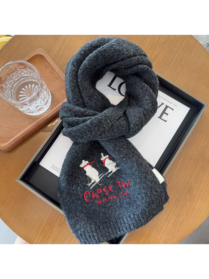 Dark Gray scarf looped on a tabletop with contrasting skiing embroidery and a partially clipped lower end