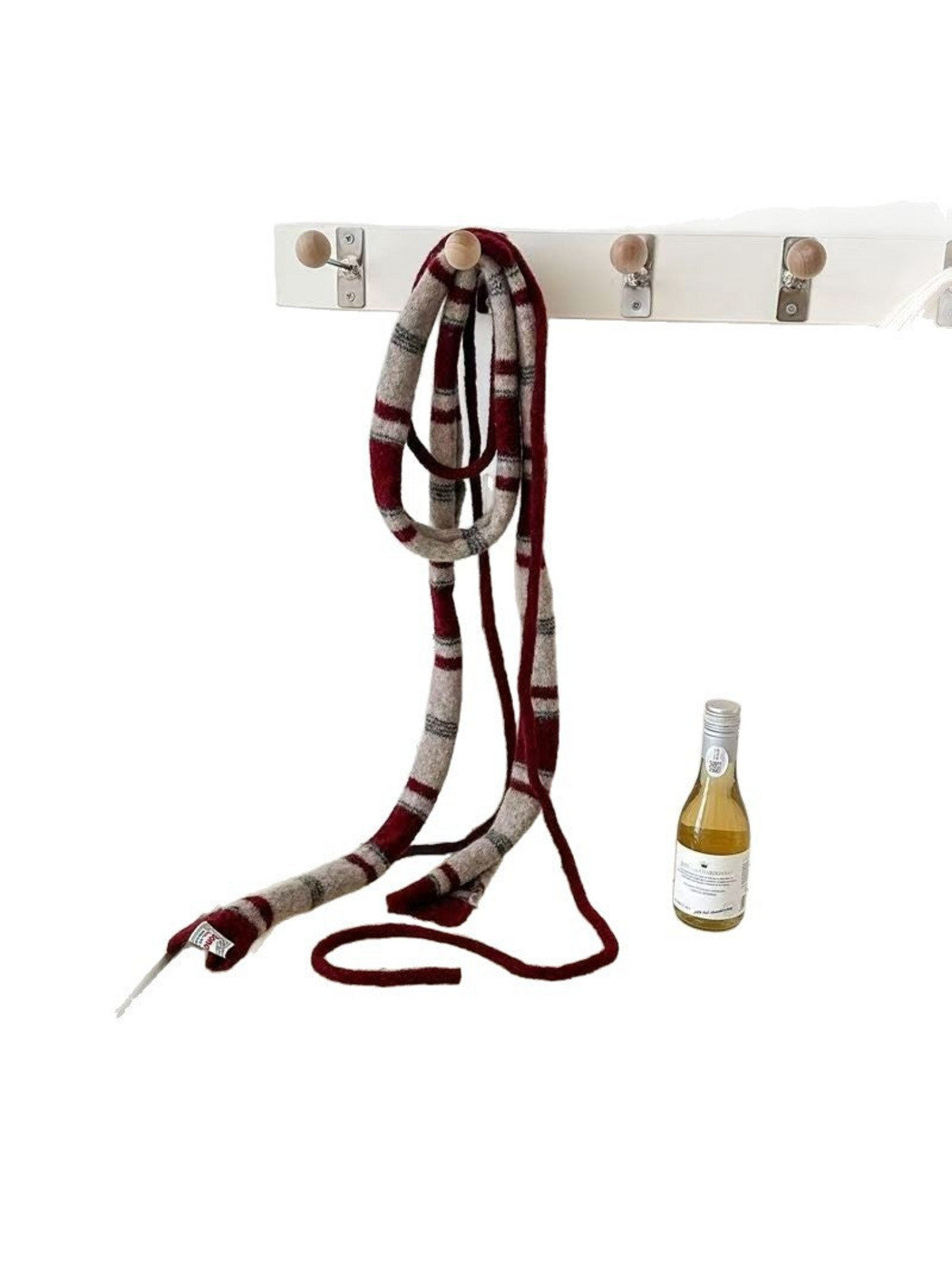 Burgundy striped scarf hanging from a wall hook with slender cords visible