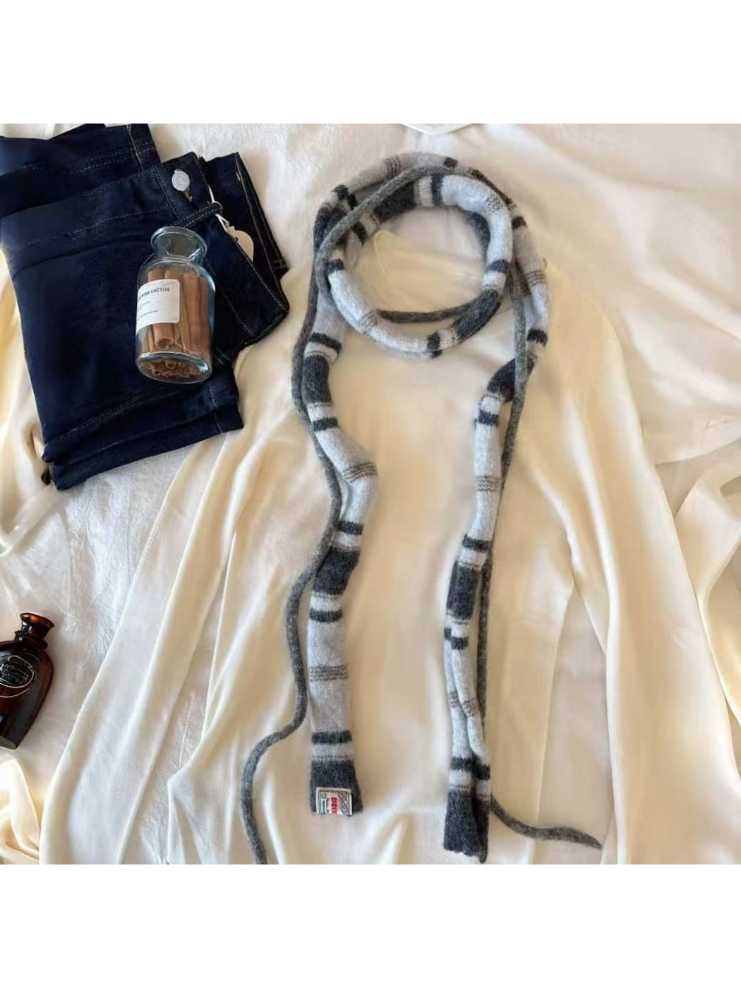 Gray striped scarf looped over a cream top with gray cords, cropped detail