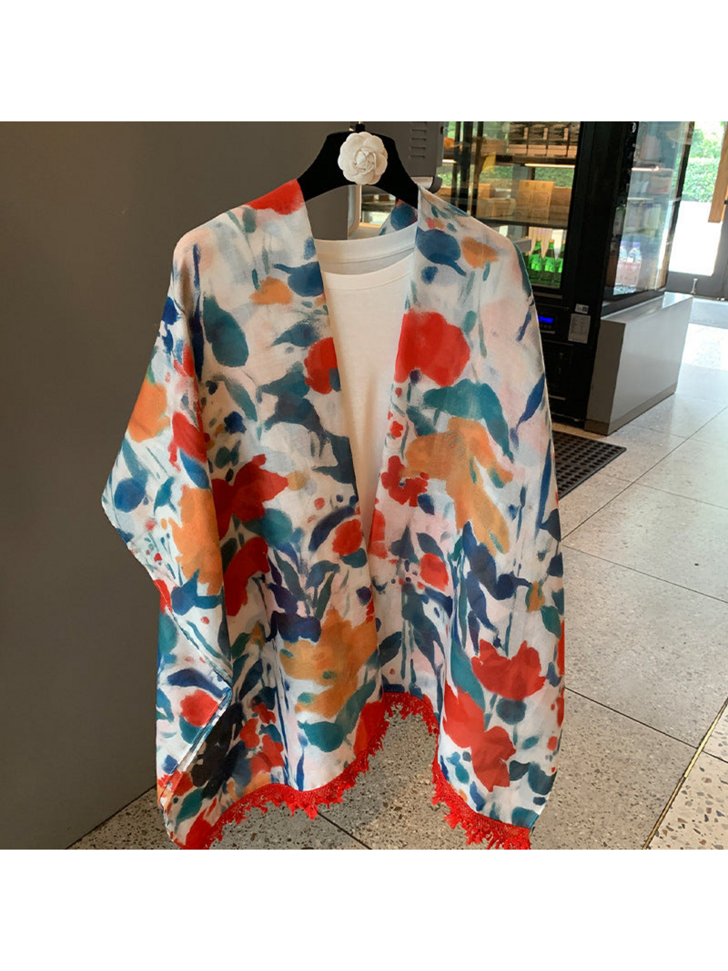 Multicolor floral scarf in an open shoulder drape with red fringed ends