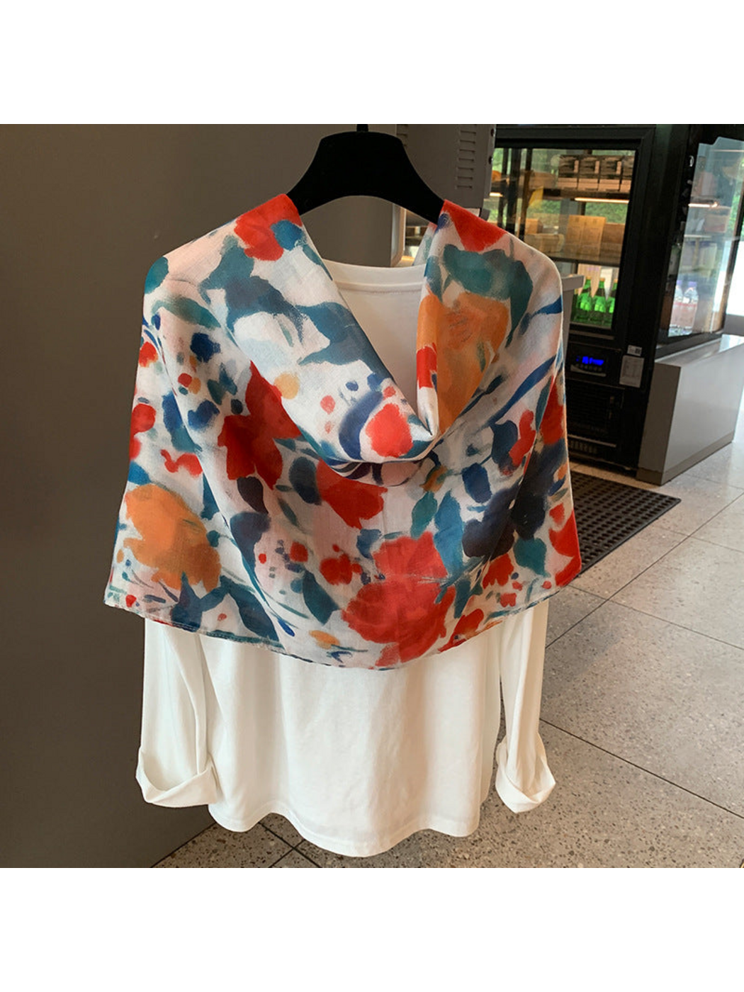 Multicolor floral scarf arranged in a broad loop over a white top