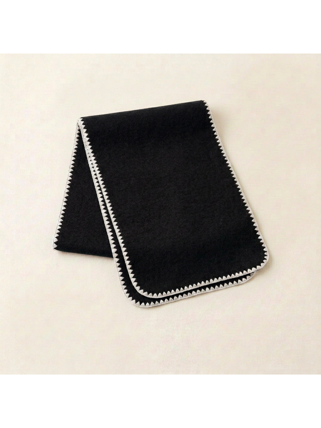 Black scarf with ivory triangular edging and rounded corners, folded view