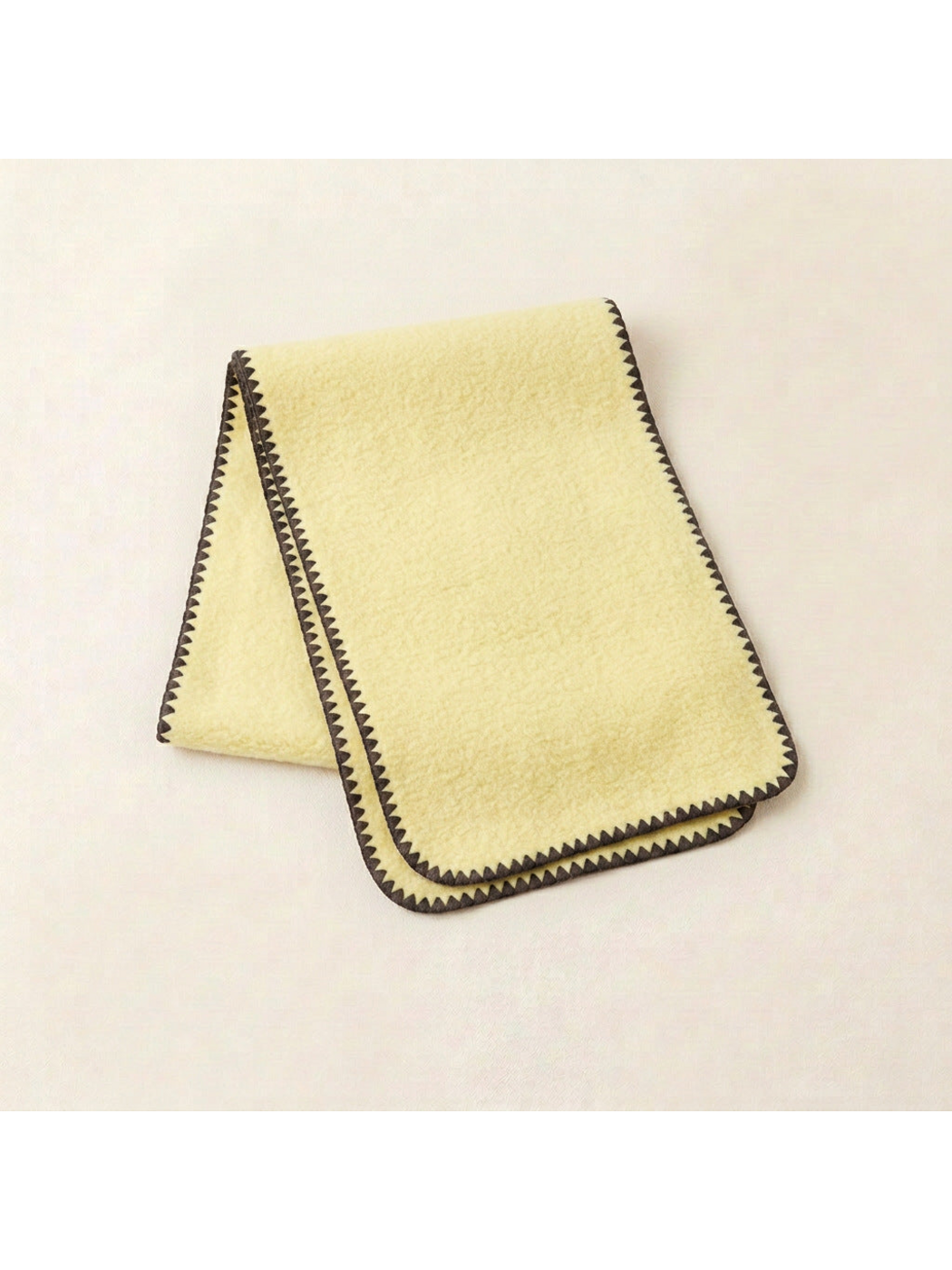Yellow scarf with dark brown triangular edging and rounded corners, folded view