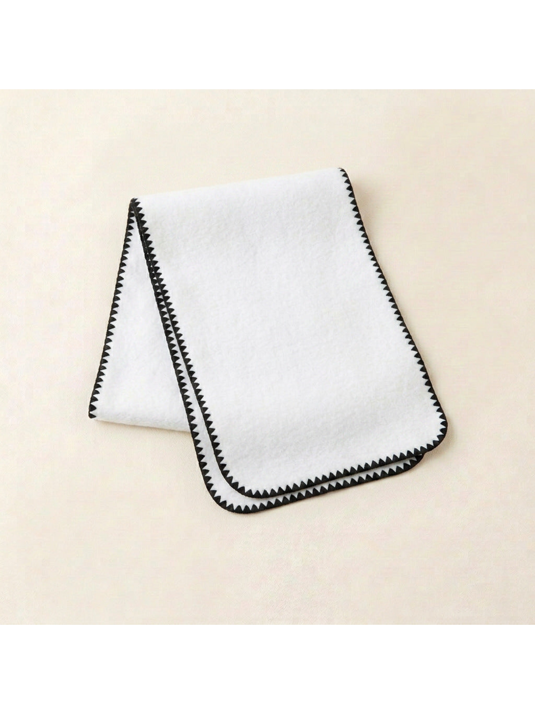White scarf with black triangular edging and rounded corners, folded view