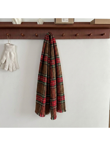 Brown tartan plaid scarf hanging from a wooden peg, showing red and green bands and fringed ends