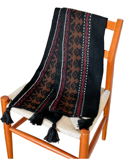 Black deer-pattern scarf draped over a chair, showing knit texture and corner tassels