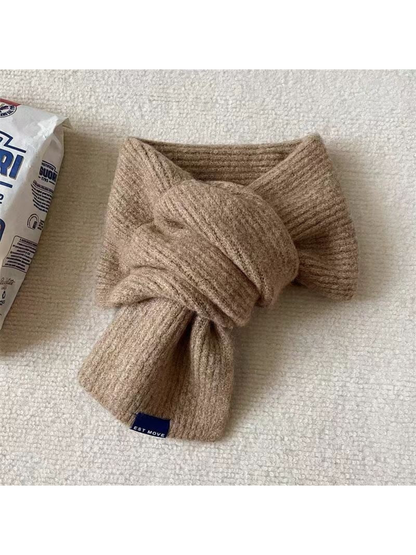 Beige ribbed scarf in a crossover arrangement with a blue end label