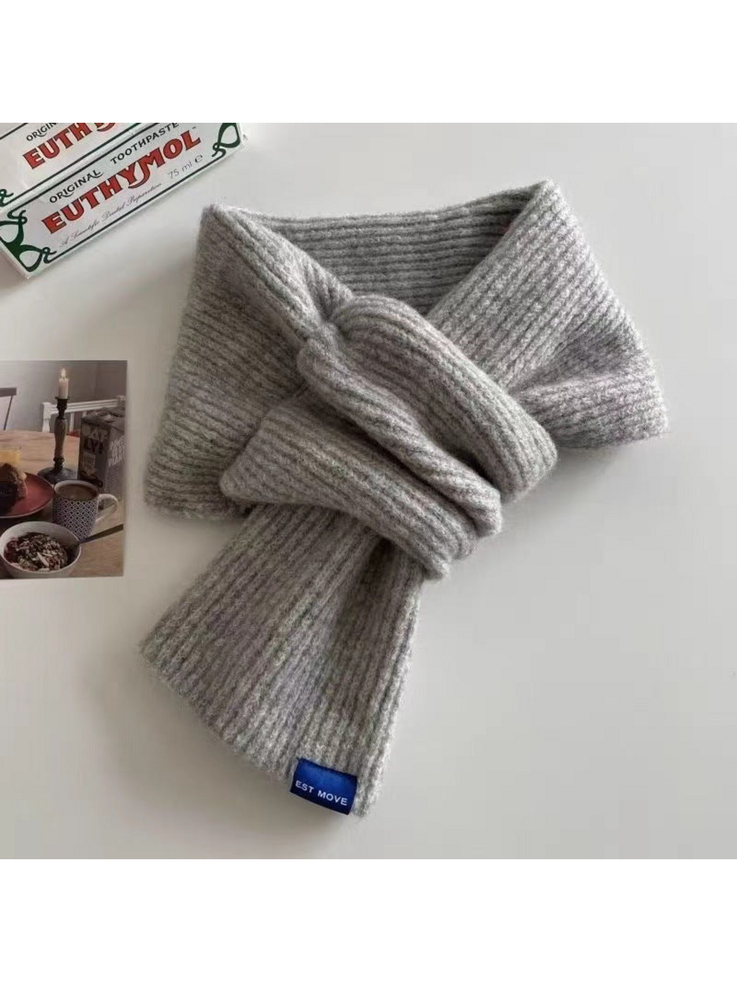 Gray ribbed scarf in a crossover arrangement with a blue end label