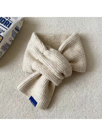 Ivory ribbed scarf in a crossover arrangement with a blue end label