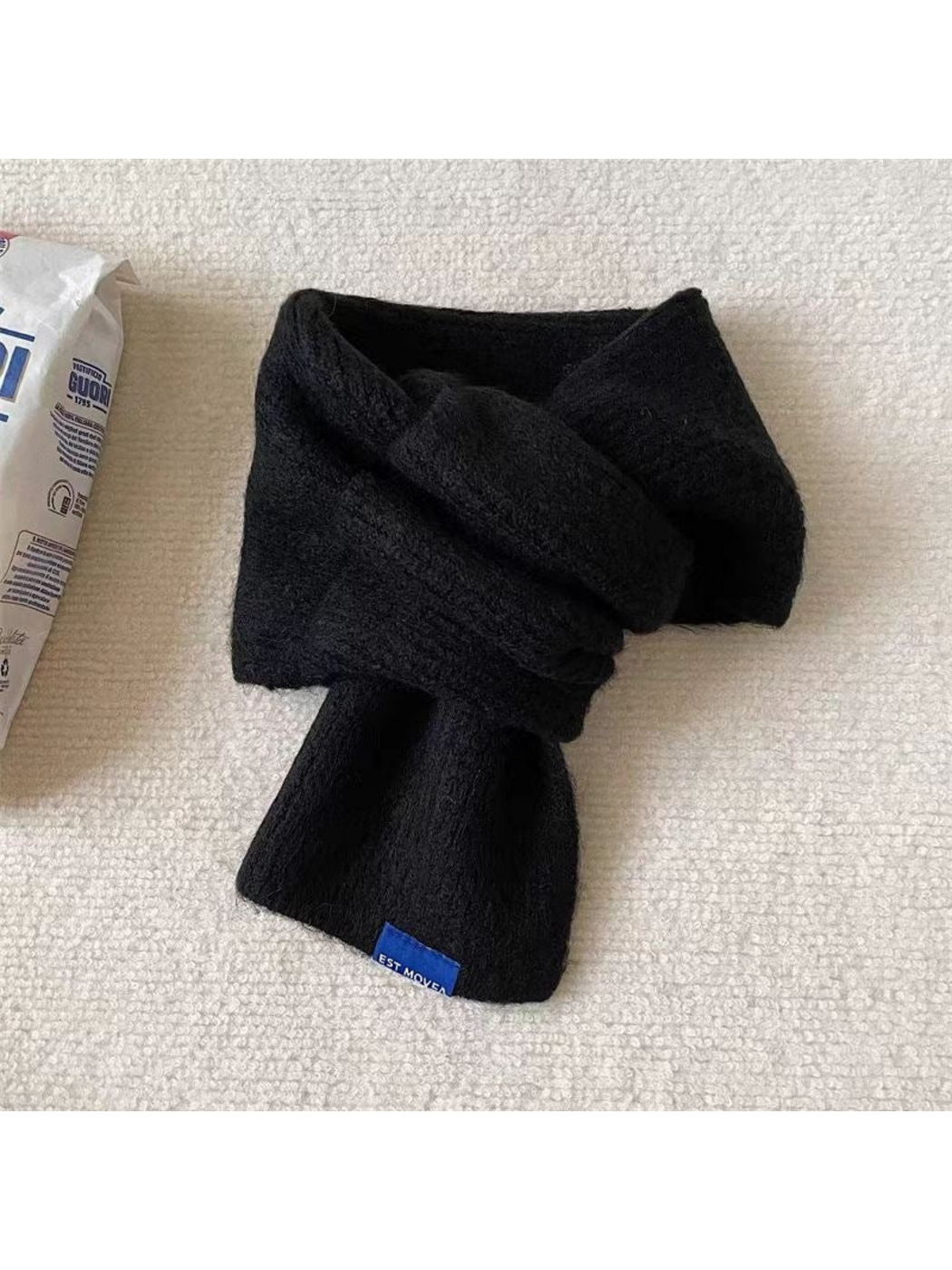 Black scarf in a crossover arrangement with a blue end label