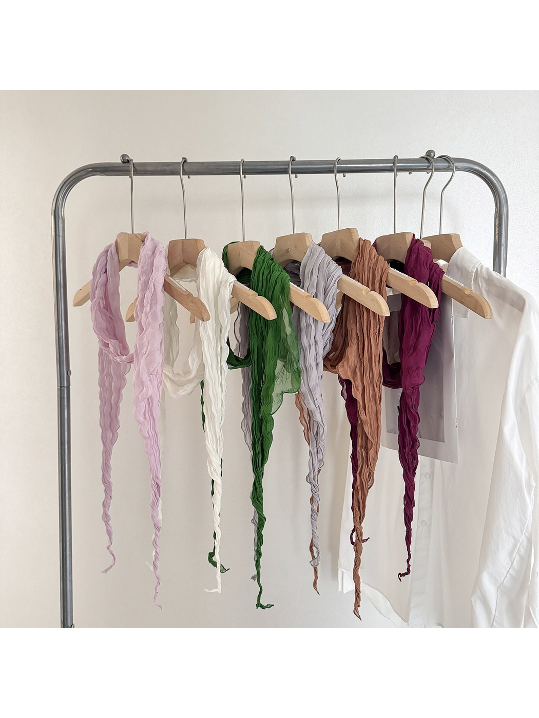 Crinkled scarves in purple, ivory, green, gray, caramel and burgundy displayed on hangers