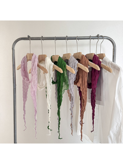 Crinkled scarves in purple, ivory, green, gray, caramel and burgundy displayed on hangers