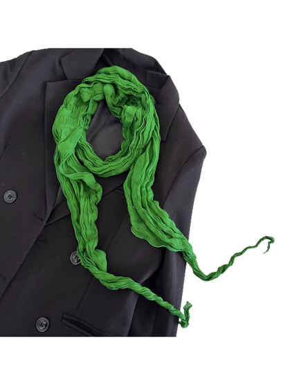 Green crinkled scarf looped over a black jacket with both tapered ends visible