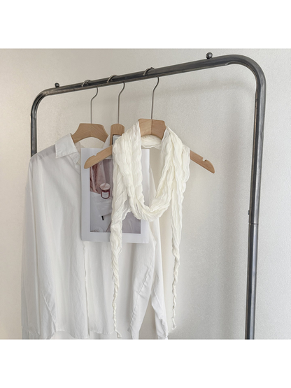 Ivory crinkled scarf looped on a wooden hanger with long tapered ends
