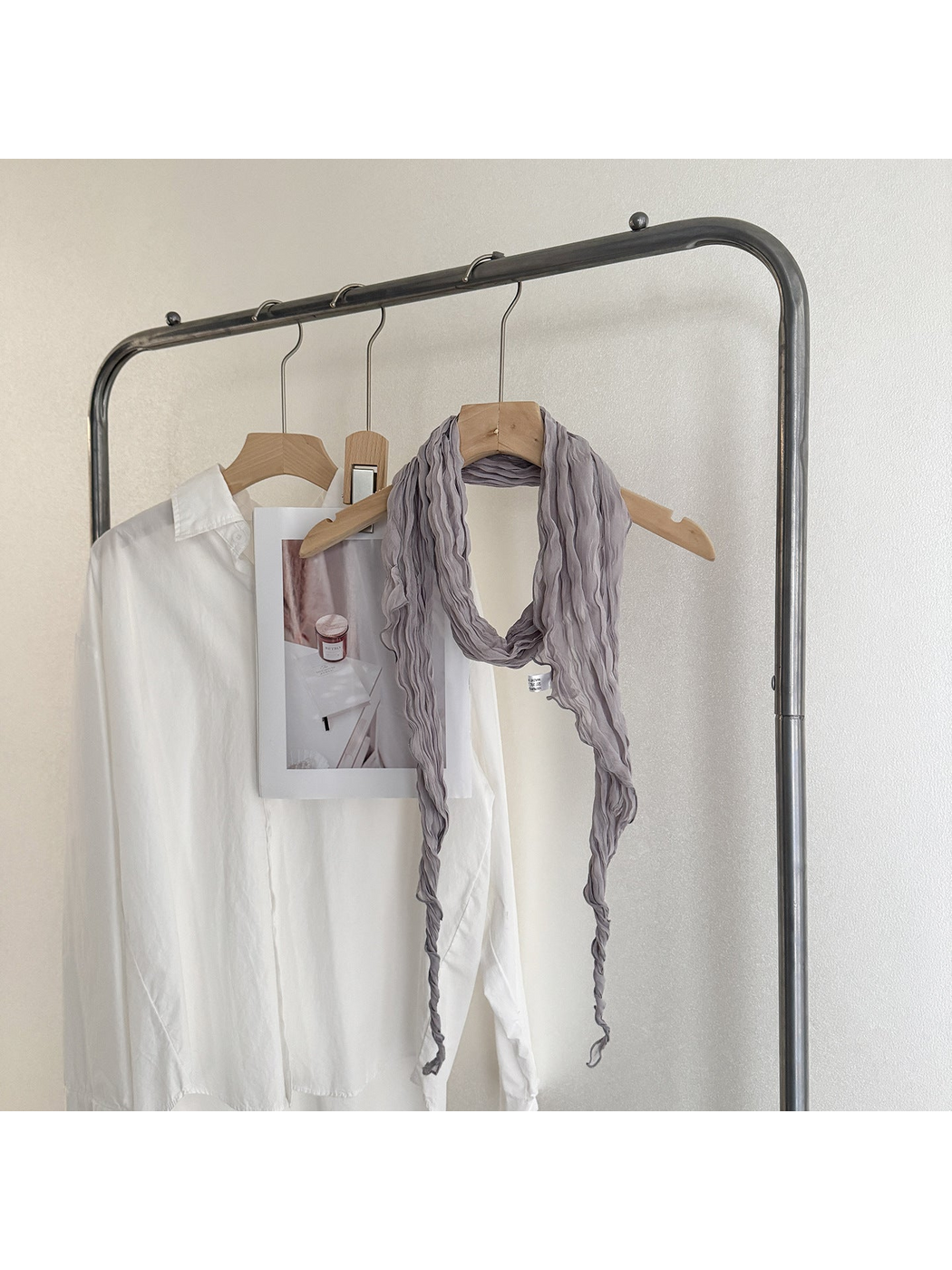 Gray crinkled scarf looped on a wooden hanger with long tapered ends