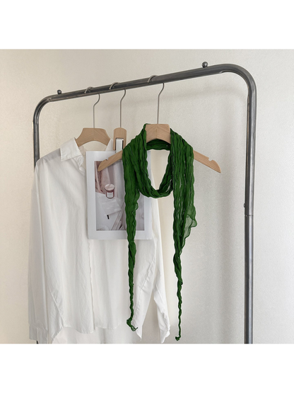 Green crinkled scarf looped on a wooden hanger with long tapered ends