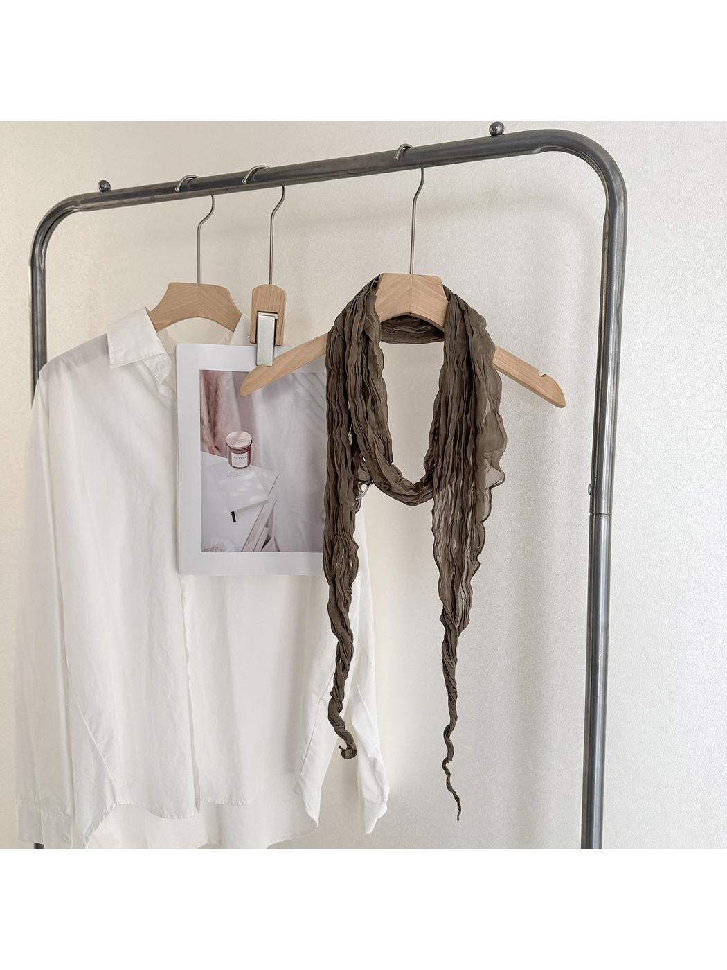 Greige crinkled scarf looped on a wooden hanger with long tapered ends