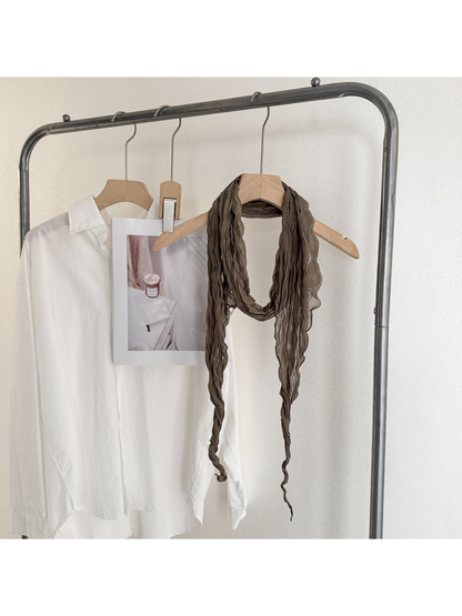 Greige crinkled scarf looped on a wooden hanger with long tapered ends