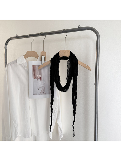 Black crinkled scarf looped on a wooden hanger with long tapered ends