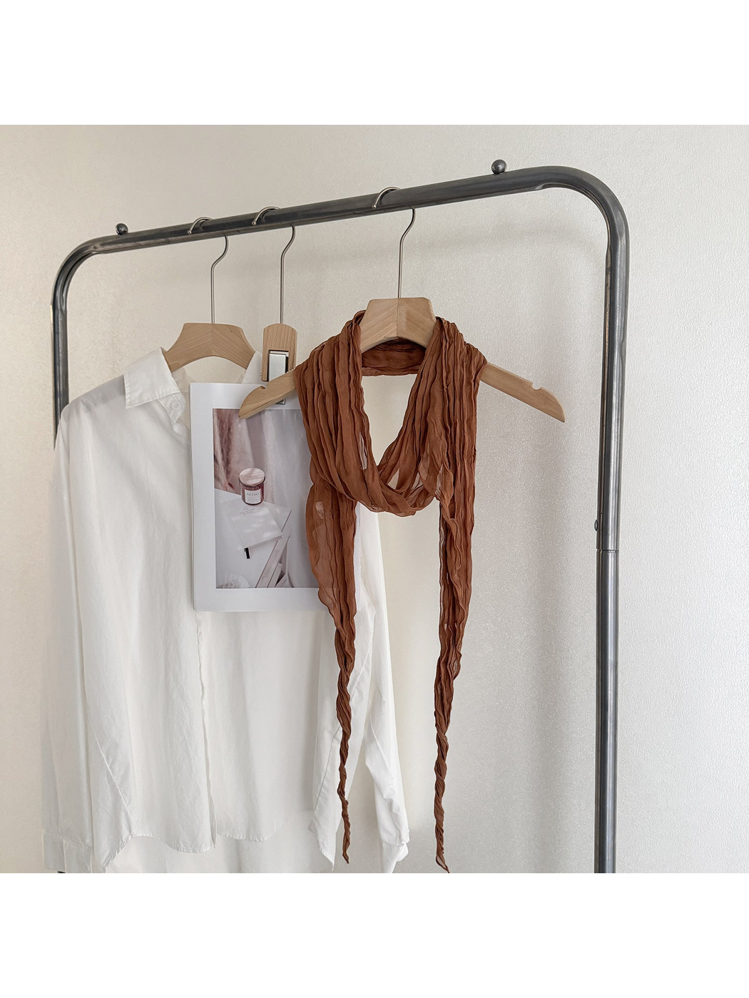 Caramel crinkled scarf looped on a wooden hanger, with one end extending beyond the lower edge