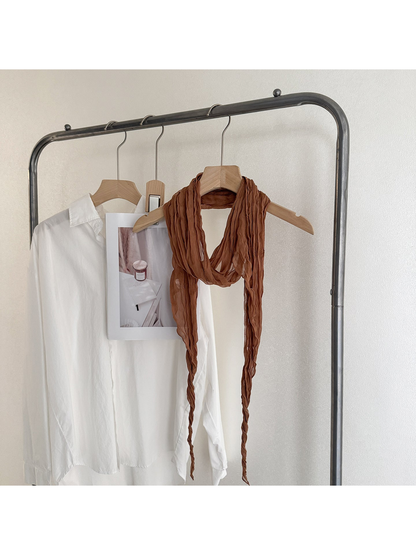 Caramel crinkled scarf looped on a wooden hanger, with one end extending beyond the lower edge