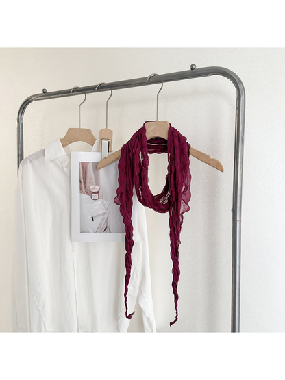 Burgundy crinkled scarf looped on a wooden hanger with long tapered ends