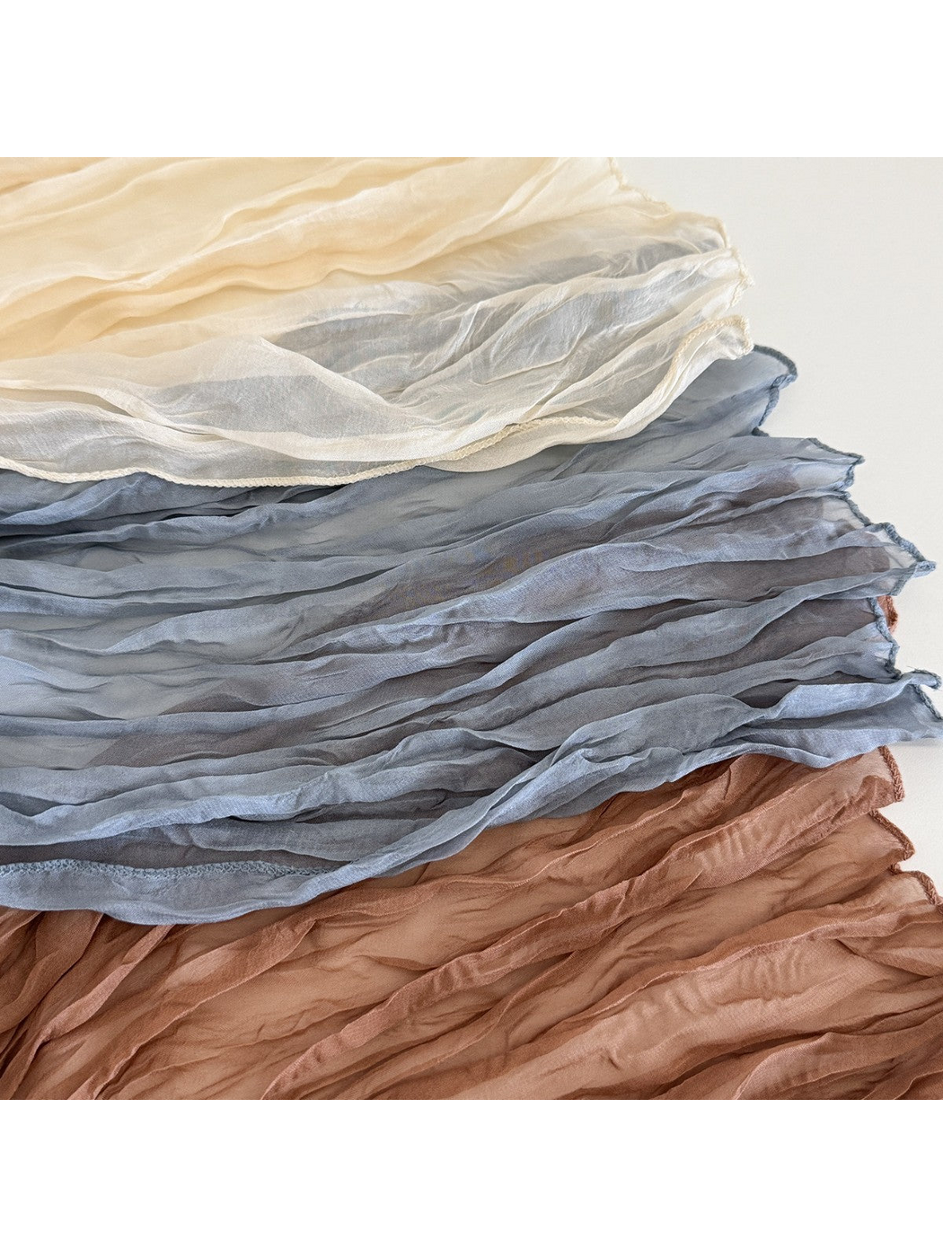 Close-up of crinkled scarves showing sheer fabric and stitched edges